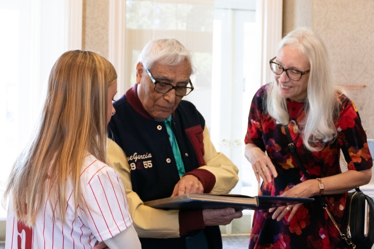 Joseph Garcia looks through his 1950 Fresno State Yearbook with his granddaughter and Dean Honora Chapman.